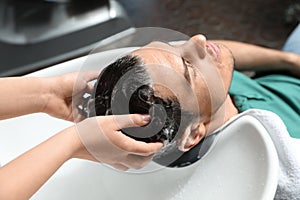 Stylist washing client`s hair at sink