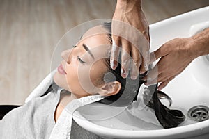 Stylist washing client`s hair at sink