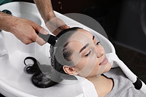 Stylist washing client`s hair at sink in salon