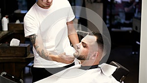 Stylist in white t-shirt and bearded client in barber shop