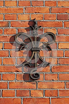 A stylistic French lily in metal mounted on a brick facade