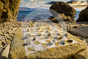 Stylized chess board drawed on a stone near a sea coast at the evening