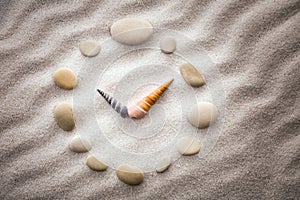 Stylized dial clock pebble and shells arrows on the sand for concentration and relaxation for harmony and balance