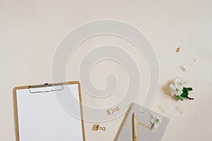 Stylized feminine or blogger desk, office desk. Workplace, white flowers of an apple tree, notebook, pen, paper clips and a tablet