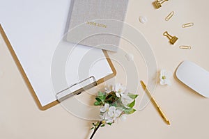 Stylized feminine or blogger desk, office desk. Workplace, white flowers of an apple tree, notebook, pen, paper clips and a tablet