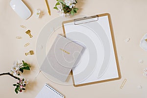 Stylized feminine or blogger desk, office desk. Workplace, white flowers of an apple tree, notebook, pen, paper clips and a tablet