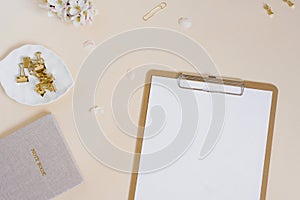 Stylized feminine or blogger desk, office desk. Workplace, white flowers of an apple tree, notebook, pen, paper clips and a tablet