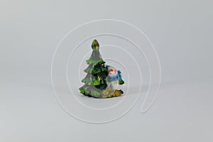 Stylized green Christmas tree and looking out from behind it snowman, subject shooting on a dark and light background.