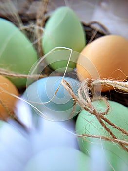 Stylized Happy Easter card,  unfocused closeup  with colorful eggs in nest , feathers and straw.