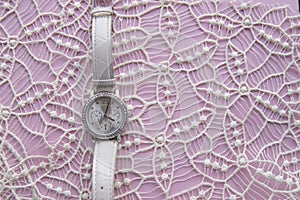 Stylized photo for business women, social networks, women`s posts, modern women`s wristwatch on a noble lace and pink background