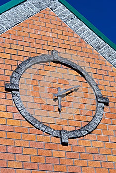 Stylized round clock on brick wall of building faÃ§ade with coni