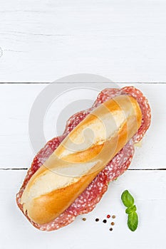 Sub sandwich baguette with salami portrait format copyspace copy space from above on wooden board