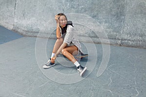 Subculture. Skater Girl Sitting On Skateboard At Skatepark Portrait. photo