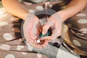 Subject medicine health and pharmaceuticals. Close-up macro young caucasian woman hands pulling out a green blister. Packing two