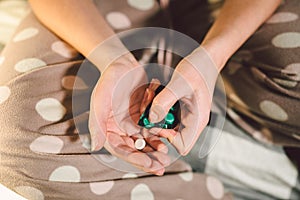 Subject medicine health and pharmaceuticals. Close-up macro young caucasian woman hands pulling out a green blister. Packing two