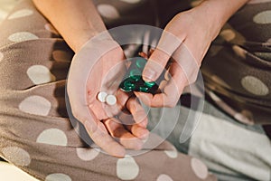 Subject medicine health and pharmaceuticals. Close-up macro young caucasian woman hands pulling out a green blister. Packing two