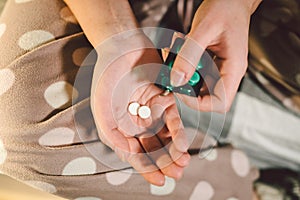 Subject medicine health and pharmaceuticals. Close-up macro young caucasian woman hands pulling out a green blister. Packing two