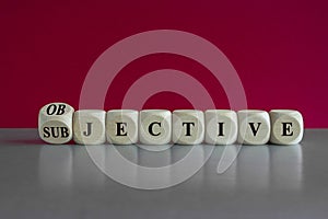 Subjective and objective symbol. Turned a cube and changes the word subjective to objective. Beautiful red background, grey table photo
