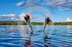 Submerged female holds two burning traditional Finnish bath whisks