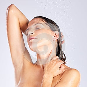 Submerging herself in a hot shower after a long day. Studio shot of an attractive young woman taking a shower against a