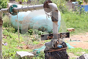 Submersible water pump connected with metal types of pipes and rusty holders on a daylight