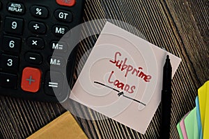 Subprime Loans write on sticky notes isolated on Wooden Table. Finance concepts photo