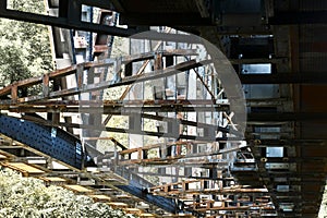 Substructure of an old iron railroad bridge with rusty girders and supports in hard light