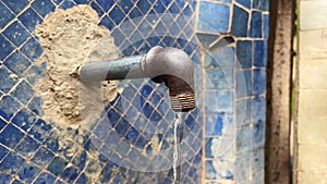 Subsurface water coming out of a metal pipe with blue mosaic in the background
