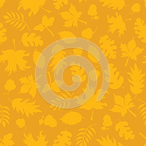 Subtle autumn background. Fall leaves seamless vector pattern. Yellow leaf silhouettes on orange. Mustard Acorns, oak tree, maple