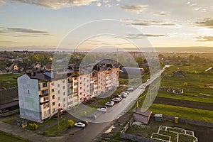 Suburb landscape, apartment building. Parked cars along bad road on spring day on blue sky copy space background