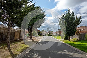 A suburban asphalt road leads to a cul-de-sac with some residential Australian homes.