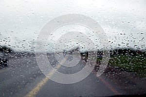 Suburban highway in rainy day. View through car window