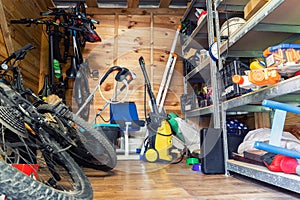 Suburban home wooden storage utility unit shed with miscellaneous stuff on shelves, bikes, exercise machine, ladder