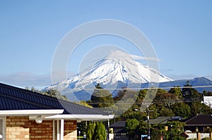 Suburban homes under snowy snow capped Mount Egmont, Taranaki New Zealand