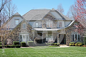 Suburban house with stone exterior and green lawn in an affluent neighborhood