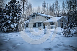 Suburban house surrounded by trees heavily covered with snow in january