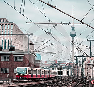 Suburban or Sbahn train of Berlin is approaching Friedrichstrasse station. Public transport in Berlin, visible typical houses and