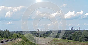 Suburbs of Ozarow (Swietokrzyskie Voivodeship). Railway tracks, a forest, a meadow on the horizon, a huge cement plant .