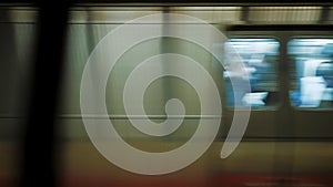 Subway train with people inside moving fast from metro station, train passing