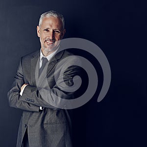 Succeeding in business with corporate charisma and authenticity. Studio portrait of a mature businessman against a dark