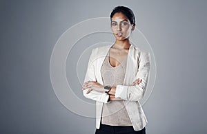 Succeeding in business with focus and fortitude. Studio portrait of a young businesswoman posing against a gray