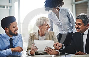 Succeeding is just so easy with the right tools. a group of businesspeople discussing something on a digital tablet in a