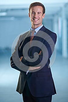 Succeeding in the realm of finance. A young businessman standing and looking confidently at the camera with his arms