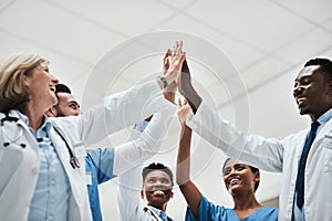 Succeeding while standing on the front lines. a group of medical practitioners giving each other a high five.