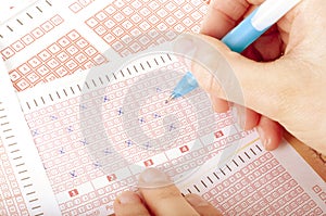 Succes concept - Person`s Hand Marking Number On Lottery Ticket With Pen