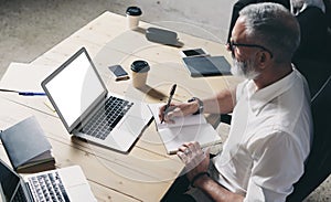 Succes and confidental adult businessman using mobile laptop computer while working at the wooden table at modern