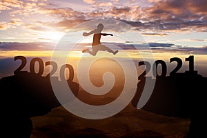 Success 2021 new year concept..Silhouette man jump between 2020 with hills and sky sunset