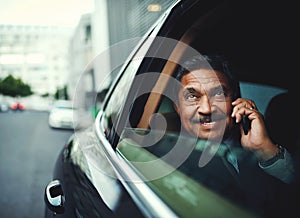 Success is in the air. a mature businessman using his phone while traveling in a car.