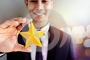 Success in Business or Personal Talent Concept. Happy Businessman in black suit Smiling and Showing a Golden Star in Hand photo