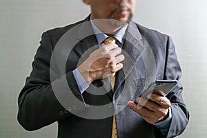 success businessman holding tie and using smart phone,thinking,front view,omni channel concept